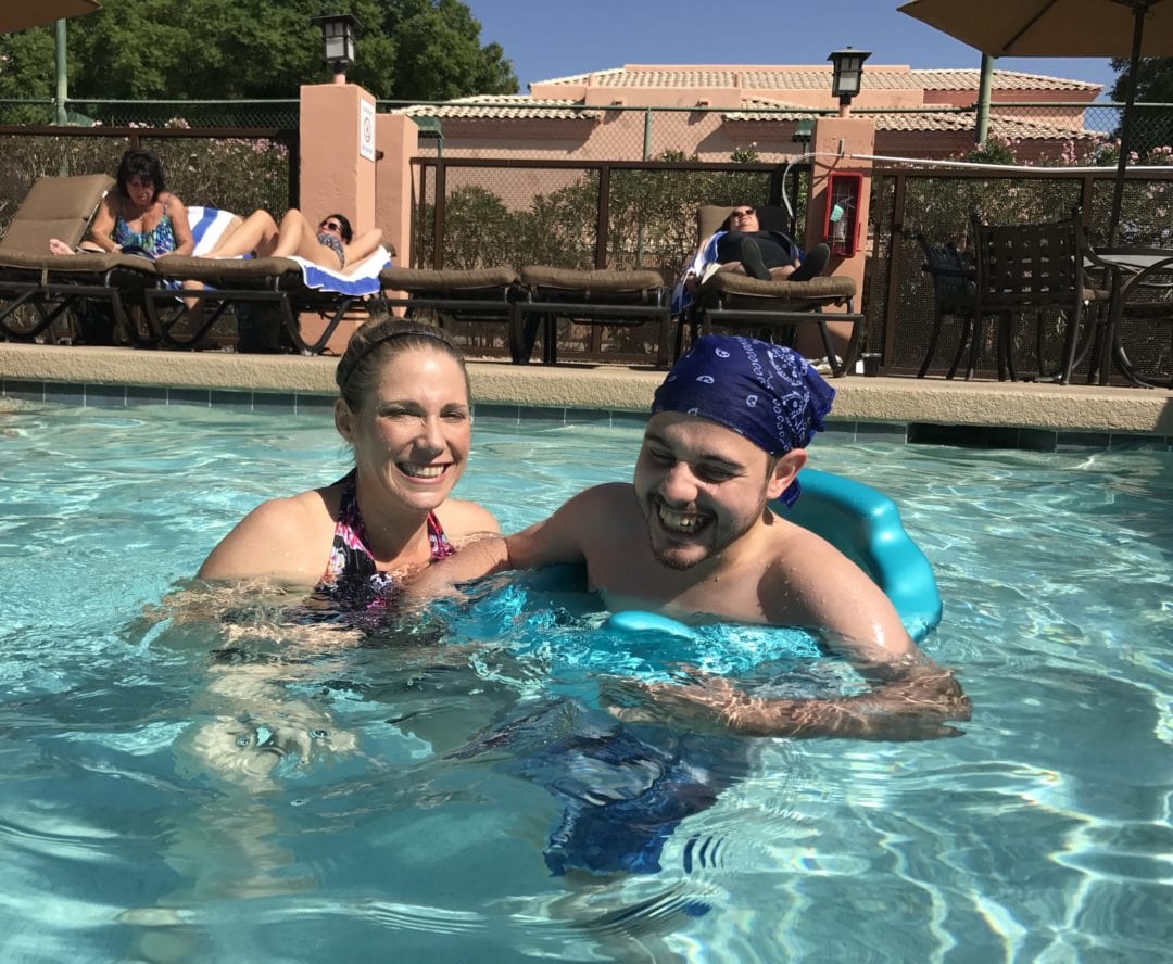 Two adults smiling in outdoor swimming pool