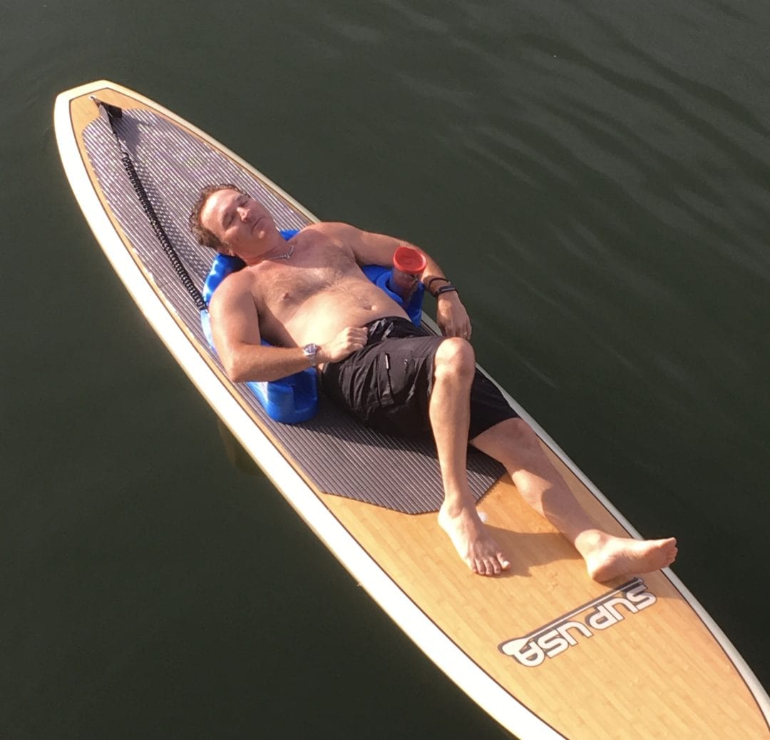 Person relaxing on paddleboard in calm water