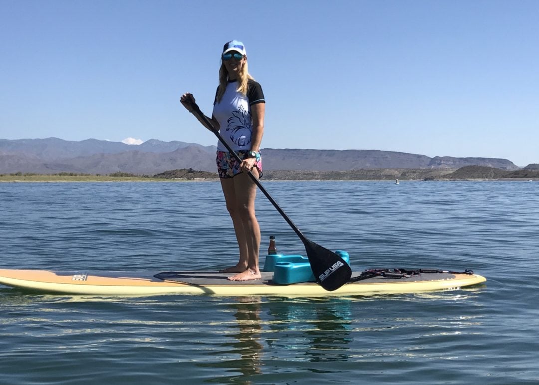 Woman paddleboarding on calm lake with mountains