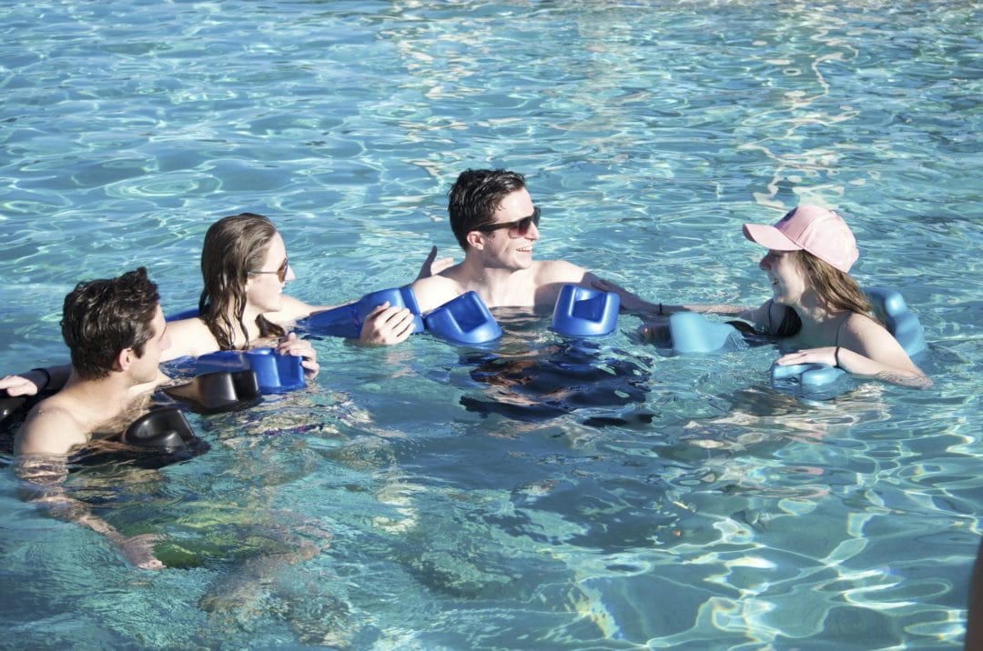 Four people floating and chatting in pool